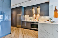 a kitchen with grey cabinets and wood floors