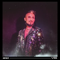 a man with a beard standing in front of a dark background