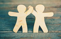 two wooden people holding hands on a wooden table