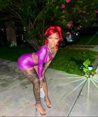 a woman in a purple dress posing on a sidewalk