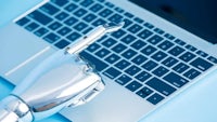 a robotic hand is holding a laptop on a blue background