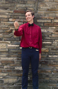 a man in a red shirt is standing next to a brick wall