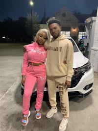 a man and woman posing in front of a car