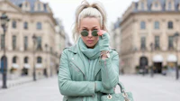 a woman in a mint green leather jacket holding a handbag