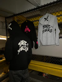 a man wearing a hoodie is standing next to a chain link fence