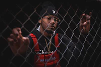 a man leaning against a chain link fence