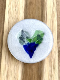 a heart made of sea glass on a wooden surface