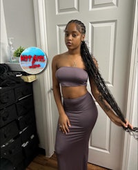 a black woman in a gray outfit posing in front of a door