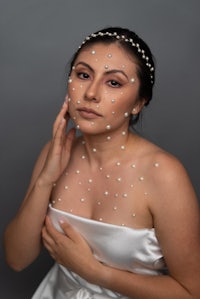 a woman in a white dress with pearls on her face