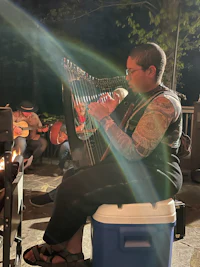 a woman playing a harp in front of a fire pit