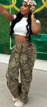 a woman in camouflage pants posing for a photo