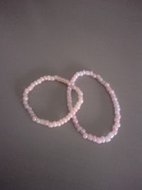 two pink beaded bracelets on a grey surface