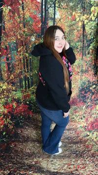 a girl posing in front of a fall forest backdrop