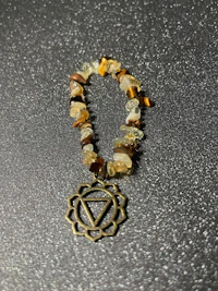a bracelet with a tiger eye stone and a chakra charm