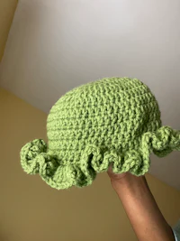a person holding a green crocheted hat