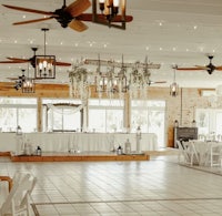a wedding reception room with white tables and chairs