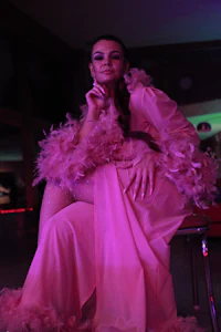a woman in a pink dress sitting on a chair