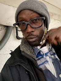 a man wearing glasses and a beanie is posing for a photo
