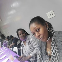two women sitting at a purple table with cell phones