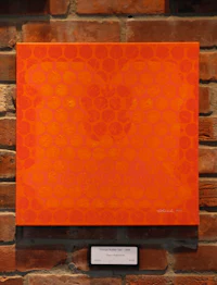 an orange painting hanging on a brick wall