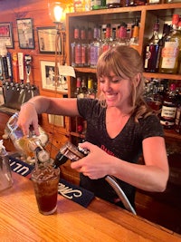 a woman pouring a drink at a bar