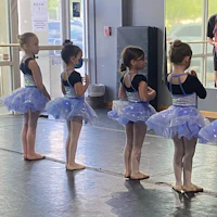 a group of young girls standing in a ballet class
