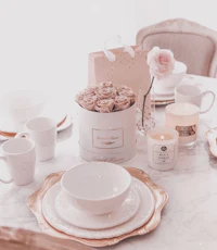 a white and gold table setting with roses and candles
