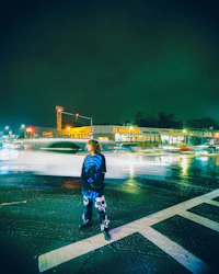 a person standing at a crosswalk at night