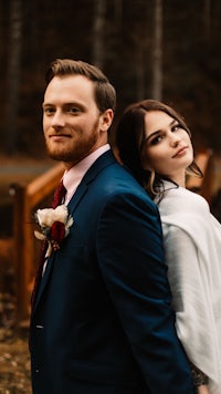 a bride and groom posing for a photo in the woods