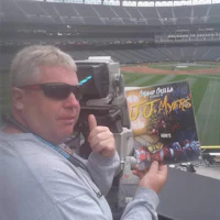 a man holding up a baseball magazine in front of a stadium