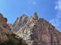 a person is walking down a rocky path near a mountain