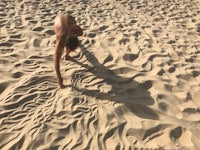a man is standing in the sand with his hands in the sand