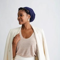 a woman wearing a white blazer and a blue turban