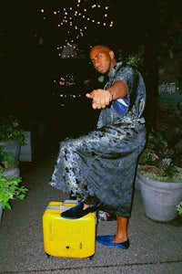 a man in a robe standing next to a yellow suitcase