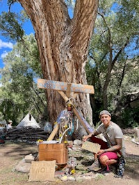 a man kneeling in front of a tree with a sign