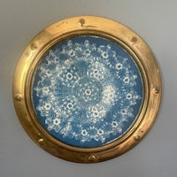 a gold frame with a blue doily hanging on the wall