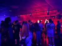 a crowd of people standing in a room with red and blue lights