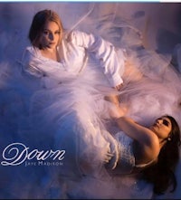 two women in white dresses laying on top of each other