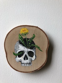 a painting of a skull with a dandelion in it