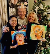 three people posing with their paintings in front of a christmas tree