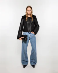 the model is wearing a black leather jacket and blue jeans