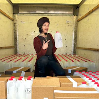 a woman sitting in the back of a truck with boxes of milk