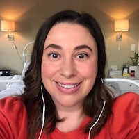 a woman in a red shirt is taking a selfie in a bed
