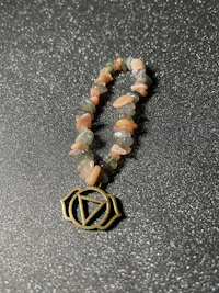 a pink stone bracelet with an om symbol on it