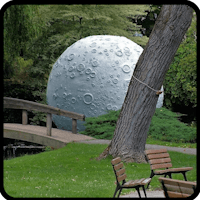 a moon sculpture in a park near a tree