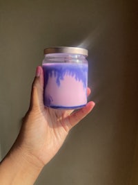 a person holding up a purple and blue candle