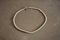 a white braided necklace with a gold clasp