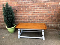 a small table with a potted plant in front of a brick wall