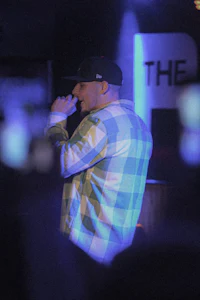 a man in a plaid shirt is singing into a microphone