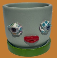 a ceramic planter with a face on it